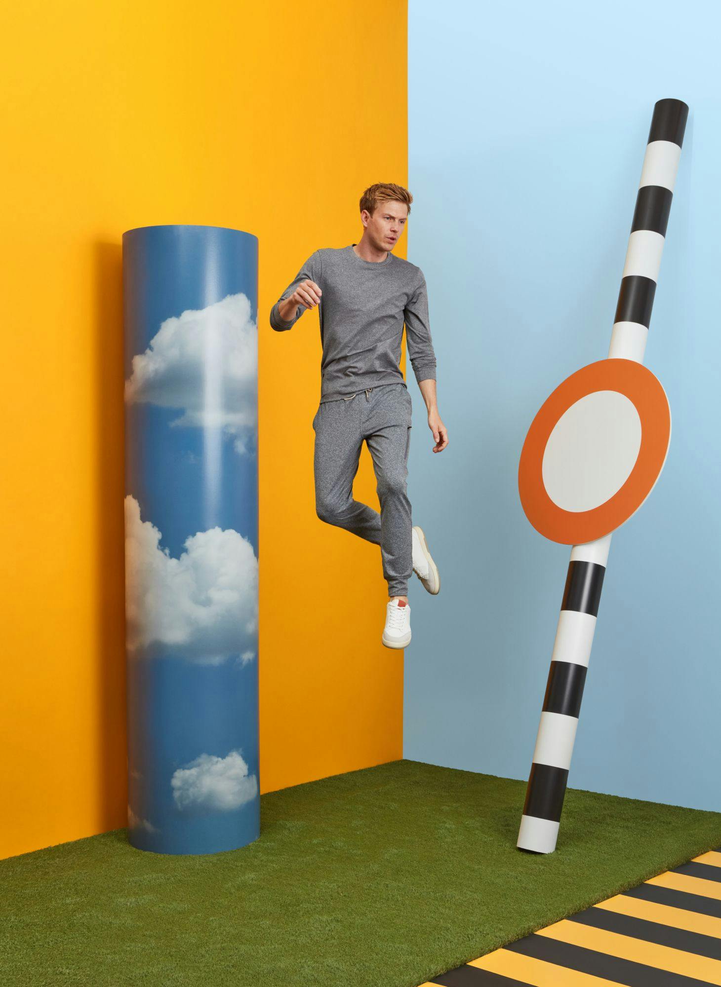 Man in grey activewear jumping against a background of yellow and blue