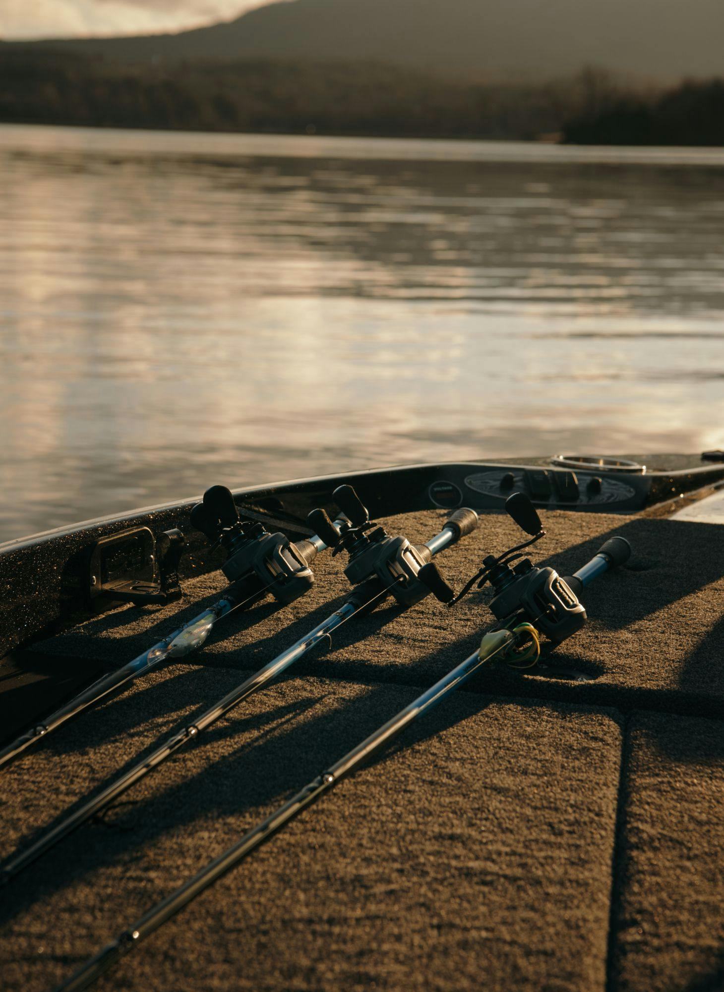 Three fishing poles on the deck of a fishing boat on a lake