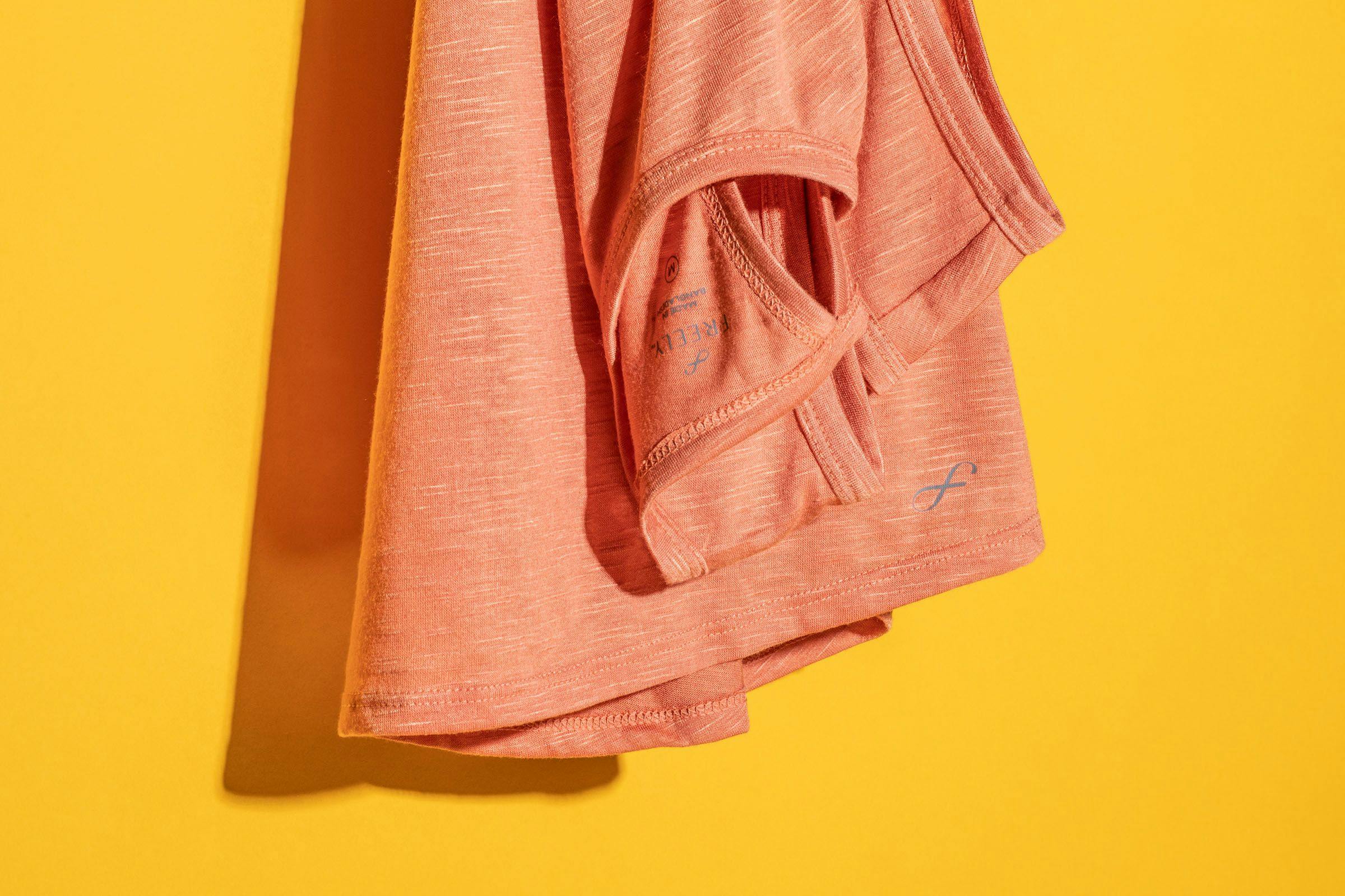 Folded Coral-Colored Tank Top Against a Yellow Background