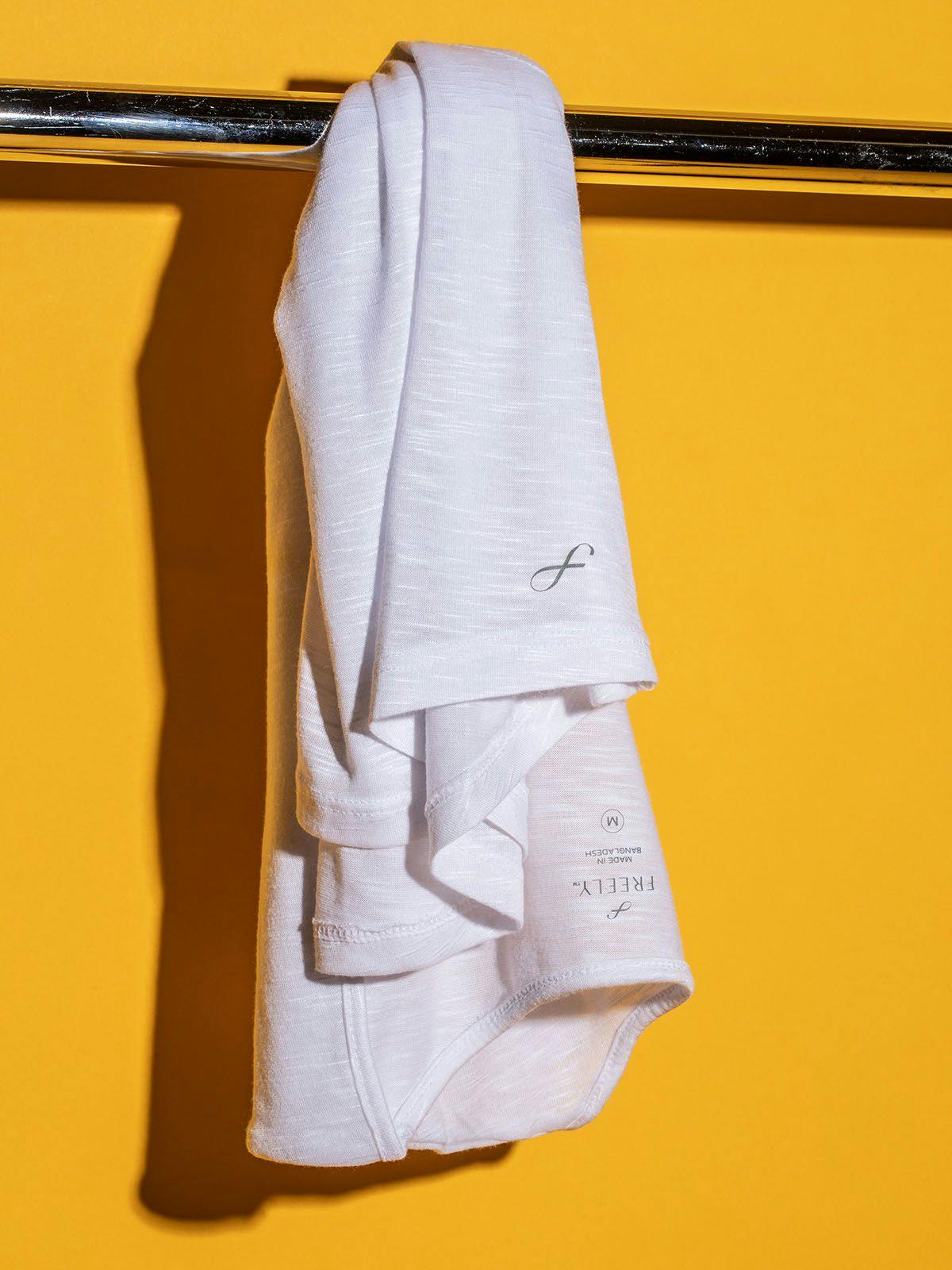 White Shirt Hanging on a Clothing Rack Against a Yellow Wall