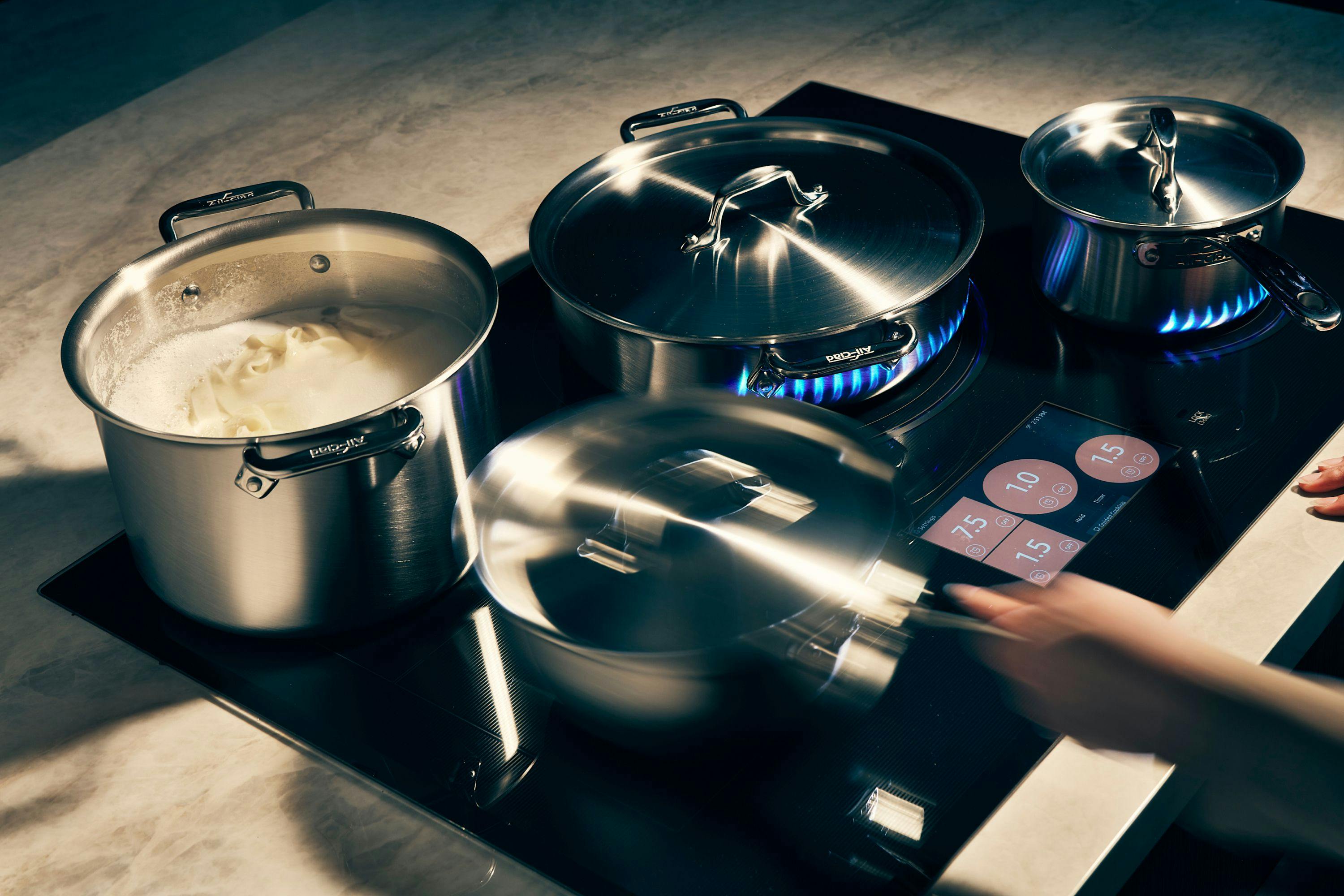 Assortment of pots on burners on a stovetop with digital display