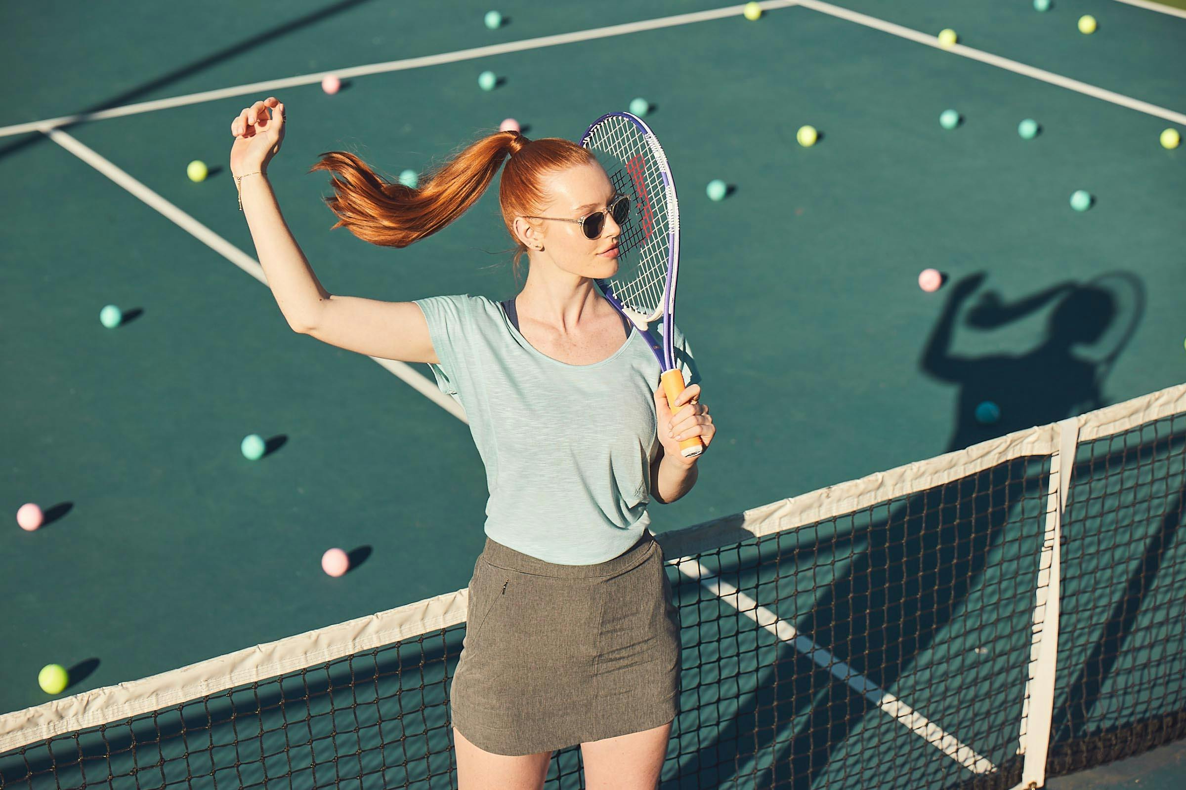 Woman Holding a Tennis Racket on a Tennis Court Littered with Tennis Balls