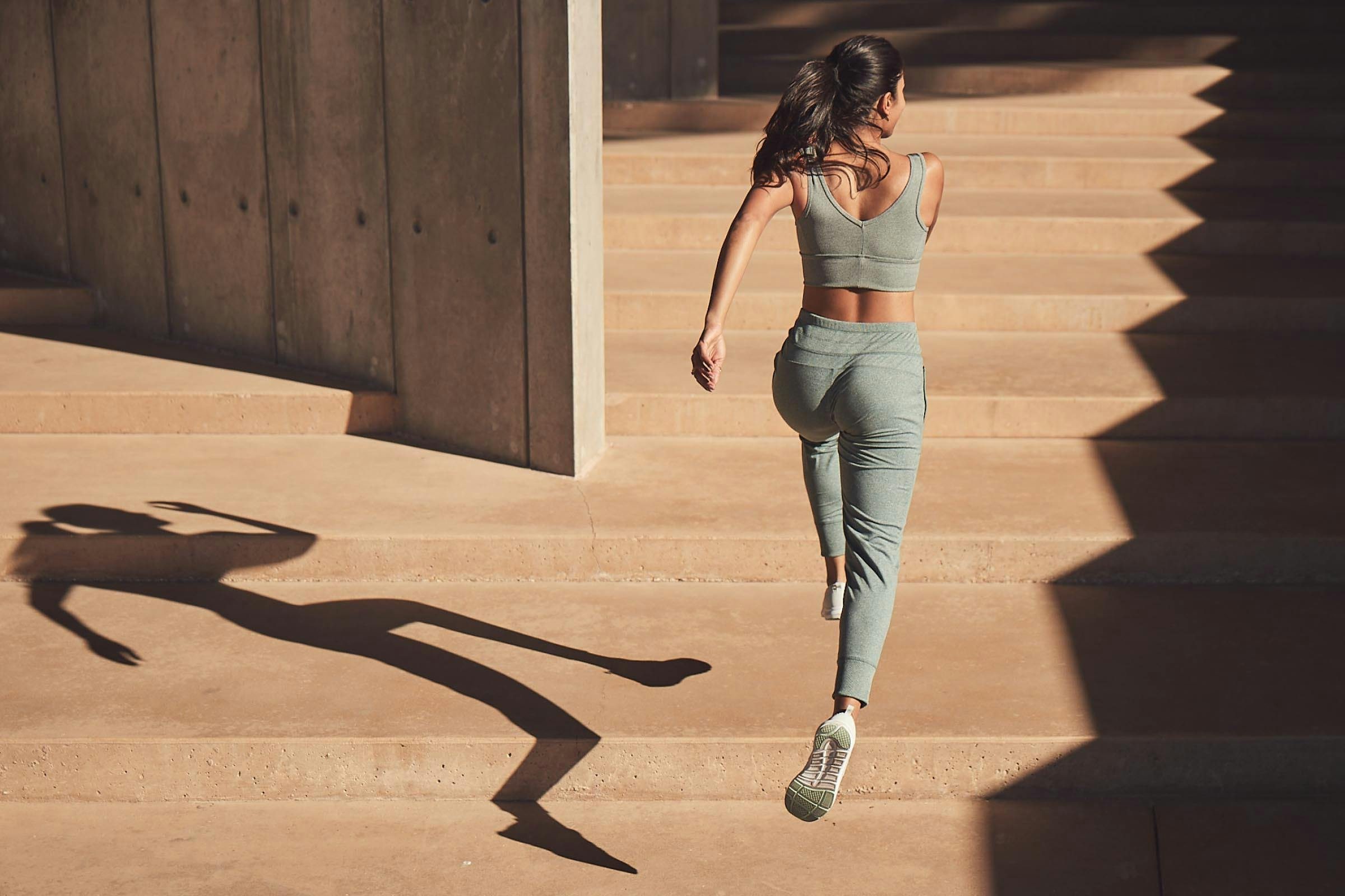 Woman Running Up a Set of Stairs in a Sage Athleisure Set