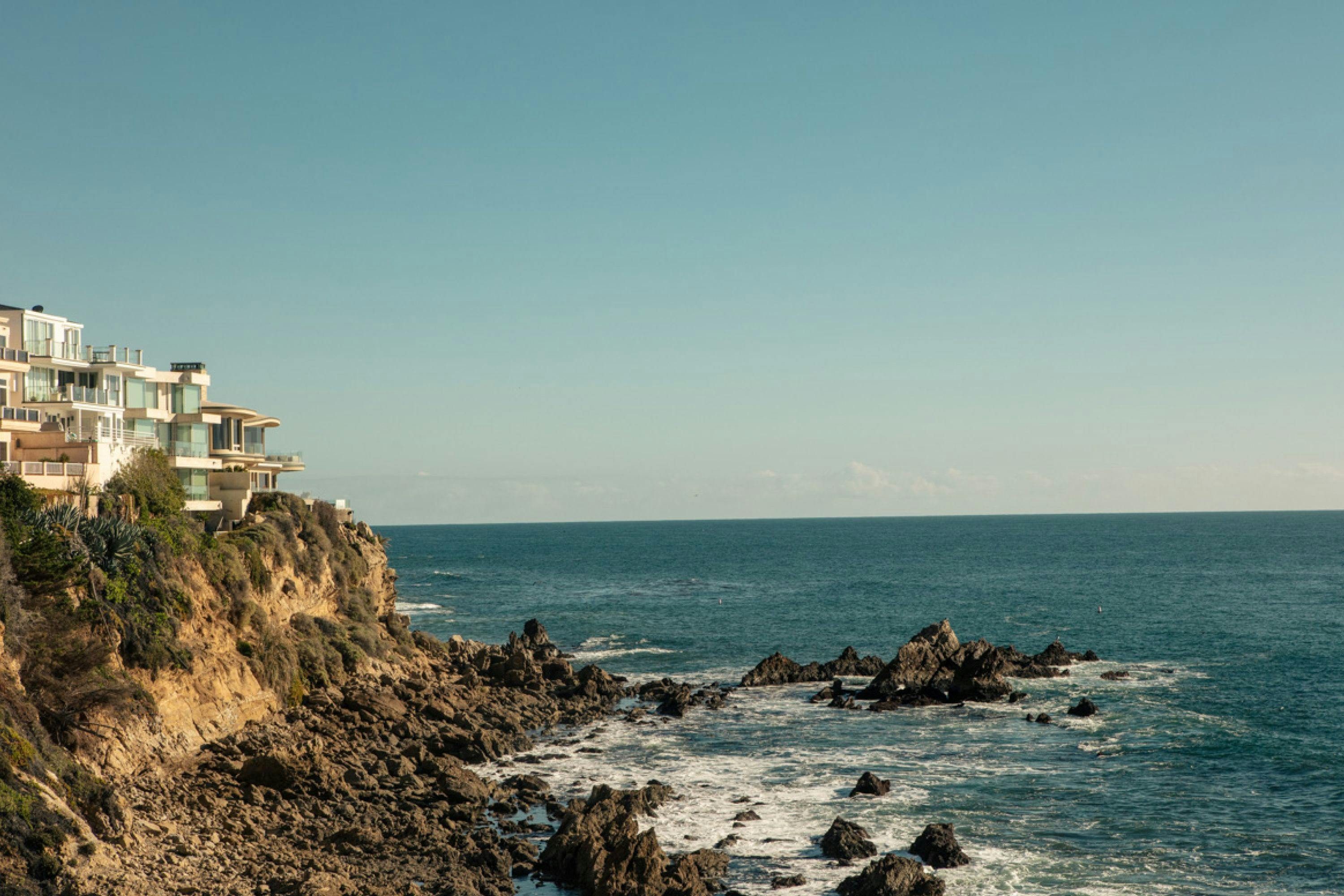 A cliffside villa near the ocean on a cloudless day